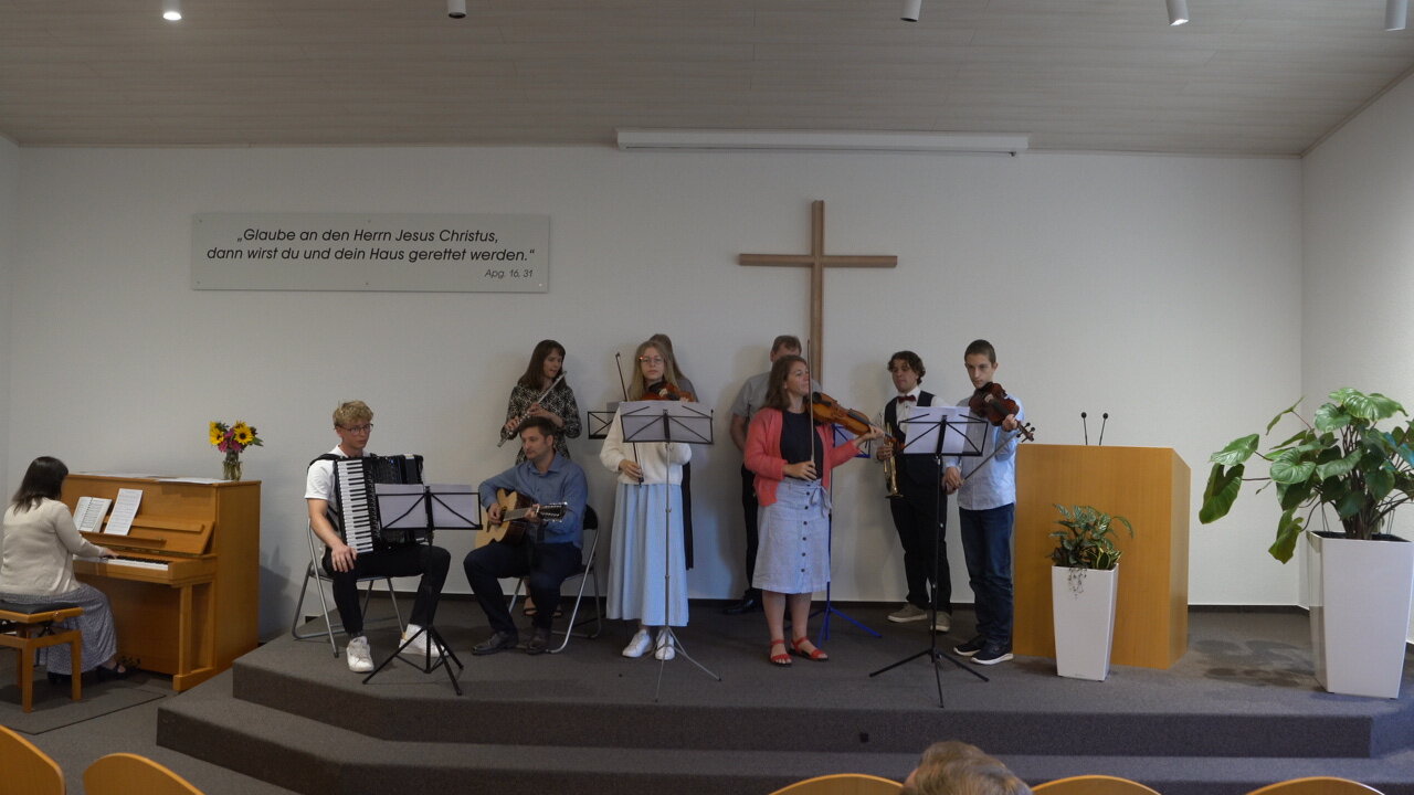 Musikgruppe mit Klavier, Akkordeon, Gitarre und Geigen beim Vortrag im Gottesdienst